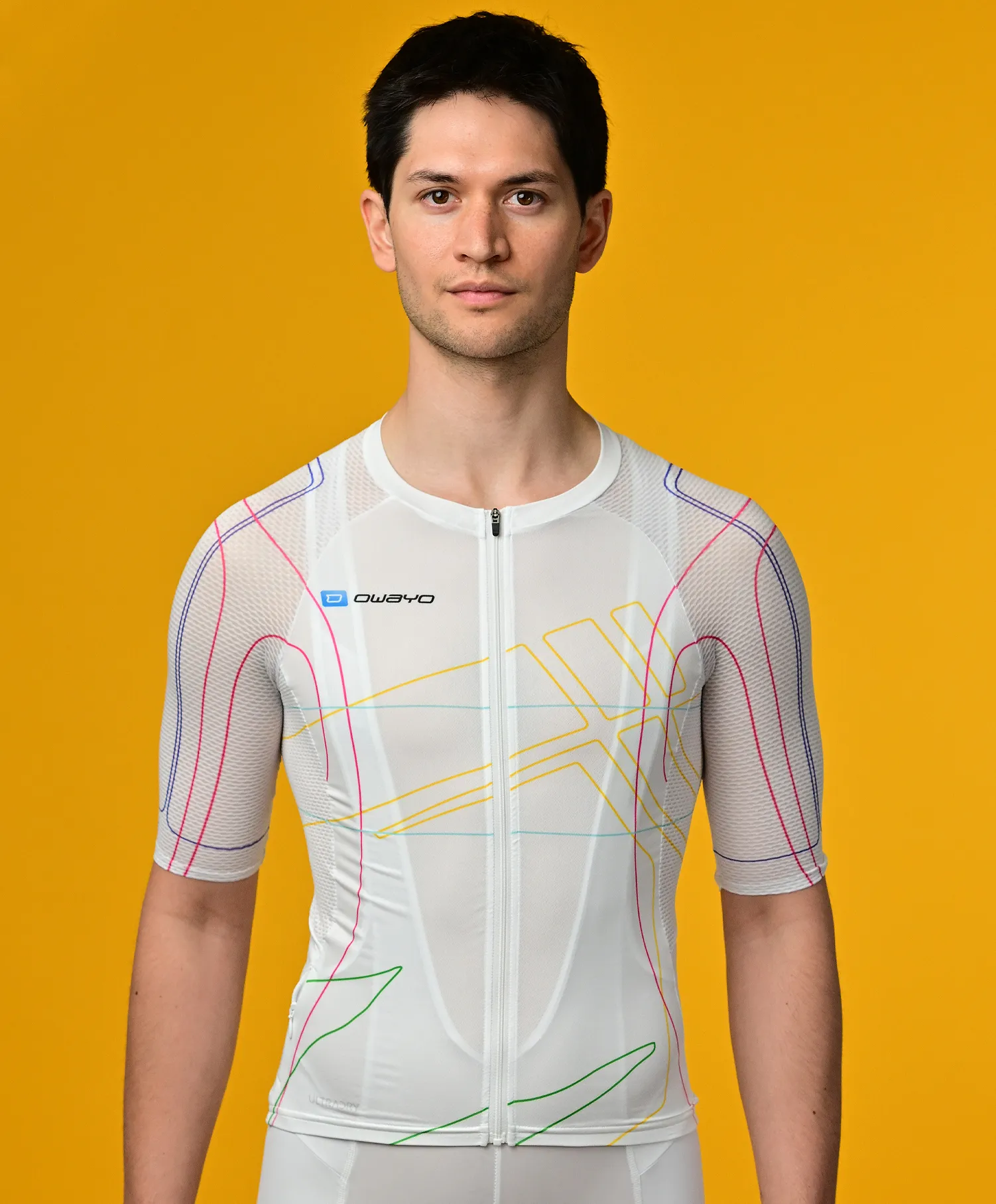 A man wears a white, short-sleeved, sport jersey with colorful lines from owayo against a yellow background.