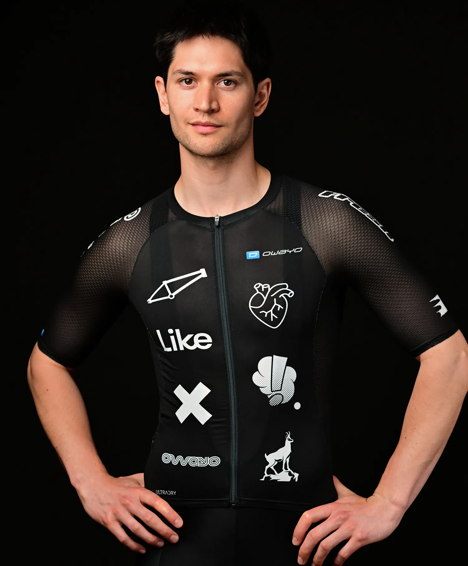 A man wearing a black customized sportswear jersey by owayo featuring various white designs including a bicycle frame, a heart, an 'X', a hand giving a thumbs up, an animal, and the word 'Like'.