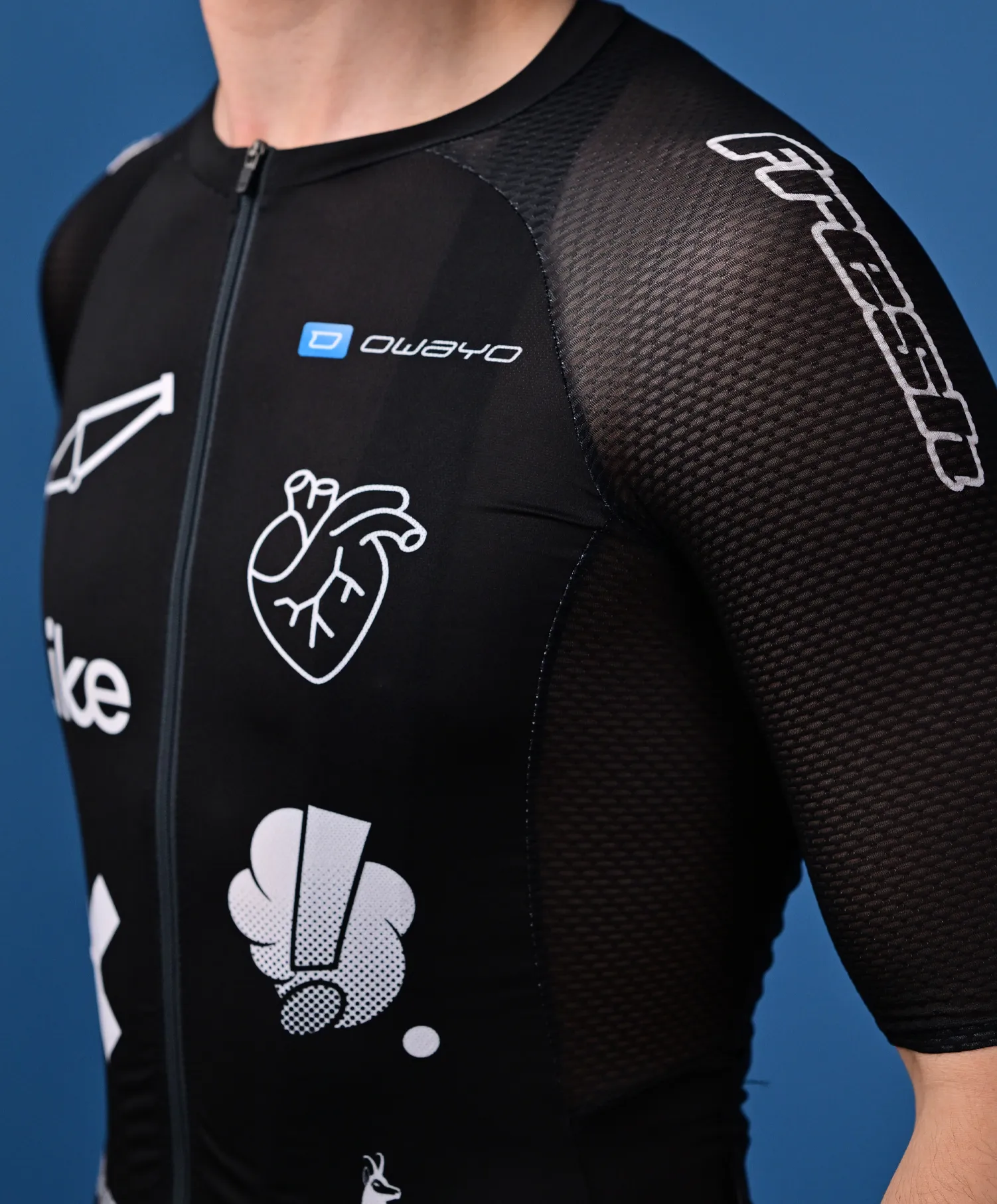 A person wears a black, sleeveless sport jersey from owayo with a front zipper, featuring various white logos and graphics, including a heart and a stylized 'O', on the chest and sleeve.